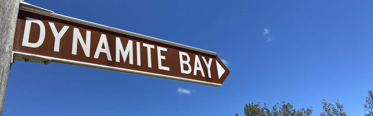 Dynamite Bay direction sign under a clear blue sky